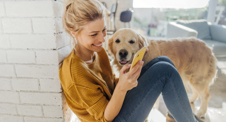 Nainen ja koira puhelimella.